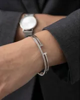 Esclava rígida de acero inoxidable con diseño abierto y detalles de circonias engastadas en una de sus bandas.