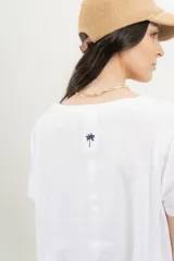 Remera blanca de algodón orgánico, con escote en V, mangas cortas y corte A-line. Cinta aplicada en la espalda con bordado de palmera.