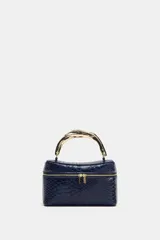 Bolso tipo vanity de color azul marino con textura de piel de serpiente en relieve. Cuenta con un asa de mano rígida metálica en tono dorado, cierre de doble cremallera y correa bandolera extraíble y ajustable.
