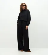 Pantalón de corte recto con cintura estructurada y lazo ajustable. Presenta un diseño básico y versátil con aberturas laterales en el ruedo.
