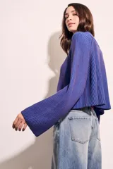 Sweater marrón de punto acanalado, con cuello alto, cierre frontal parcial con cremallera y manga larga.