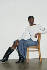 Camiseta de cuello barco y manga larga con diseño asimétrico en el bajo. Presenta un corte entallado con cierre lateral mediante cremallera oculta.