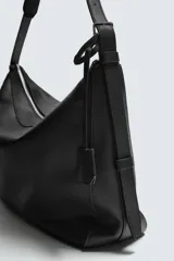 Bolso de hombro de diseño minimalista confeccionado en piel de alta calidad. Cuenta con un compartimento principal con cierre de cremallera, interior con bolsillos organizadores y asa de hombro fija. Incluye un detalle de llavero colgante.
