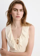 Vestido midi recto color beige sin mangas, con cuello en V con solapa de volantes bordados y cordones entrecruzados en el escote.