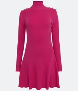 Vestido corto de punto acanalado negro, con cuello alto, mangas largas y falda acampanada. Presenta detalle de botones dorados en los hombros.