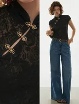 Top de encaje floral negro, al cuerpo, con cuello alto estilo mandarín y broches decorativos dorados en el frente.