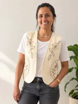 Chaleco de color natural con escote en V y diseño sin mangas, decorado con delicados bordados florales en tonos tierra.