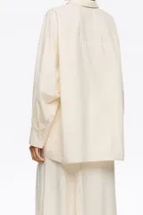 Camisa oversize de algodón color celeste, con cuello camisero, botones frontales y mangas largas ranglán con puños abotonados. Presenta pespuntes a contraste en toda la prenda.