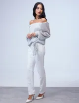 Blusa plateada de gasa lurex con escote off-shoulder, mangas largas abullonadas y terminación anudada en el ruedo.