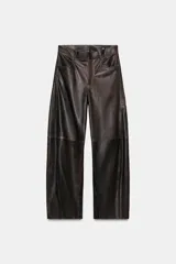 Pantalón de tiro medio confeccionado en piel 100%, color marrón oscuro con acabado ligeramente desgastado. Presenta un corte ancho y recto, con costuras visibles que simulan paneles y bolsillos delanteros y traseros.