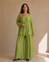 Camisa holgada de seda en color verde lima, con cuello en V, mangas largas amplias y cierre frontal de botones claros.