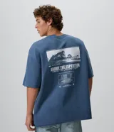 Remera oversized de algodón color azul, de manga corta y cuello redondo, con diseño fotográfico y texto impreso en la espalda.