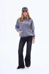 Buzo tipo canguro de felpa color gris, con capucha, bolsillo frontal tipo canguro y estampa frontal con texto y estrellas.