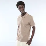 Remera polo de piqué de algodón color beige, con cuello y puños con ribete blanco, cierre frontal con botones y pequeño logo bordado en el pecho.