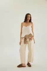 Top lencero blanco con escote en V y detalles de encaje en el borde superior, con tirantes finos y diseño fluido.
