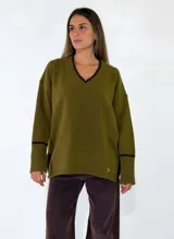 Sweater de punto color bordó con cuello en V, manga larga con puños acanalados y detalle de franja en contraste. Presenta un diseño holgado con aberturas laterales.