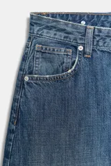 Jeans de tiro medio con diseño balloon, cinco bolsillos, cierre frontal con cremallera y botón metálico. Presenta un acabado en puño elástico en la parte inferior.