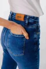 Jean azul claro de corte flare con aberturas en los tobillos y detalles rotos en las rodillas y muslos.