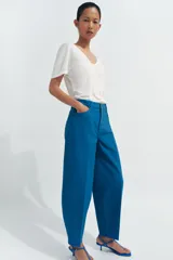Jeans de tiro alto con corte tapered y largo al tobillo. Presenta cinco bolsillos, trabillas en la cintura, cierre frontal con cremallera y botón, y detalle de raya planchada en el frente.