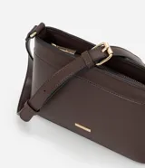 Bolsa bandolera de estructura firme en color marrón oscuro, con cierre de cremallera metálica y correa larga ajustable con hebilla.