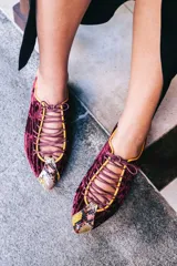 Zapatos tipo oxford de terciopelo rayado en color granate, con detalles de cuero con estampado de piel de serpiente en el talón y la puntera. Presentan cordones finos y ribetes en color amarillo.