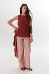 Top sin mangas color celeste claro, con cuello redondo y bolsillo frontal. Presenta costuras a contratono y un pequeño tajo en la parte trasera.