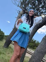 Bandolera pequeña de diseño moderno, confeccionada en tafeta liviana y resistente. Cuenta con cierre superior, correa ancha ajustable y logo frontal de la marca.