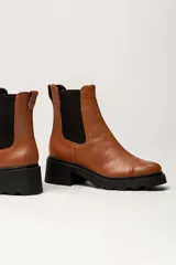 Bota tipo Chelsea de cuero color verde oliva, con paneles laterales elásticos negros y suela track de goma negra con taco cuadrado.