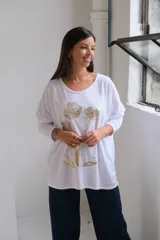 Remera blanca de corte holgado y manga larga, con estampado floral en color dorado en el frente.