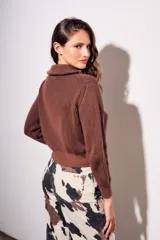 Campera tejida de algodón con cierre frontal completo y cuello alto. Presenta una textura acanalada vertical y puños y ruedo elásticos.