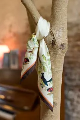 Pañuelo cuadrado de seda con estampado botánico y de aves, inspirado en ilustraciones históricas de Dámaso Antonio Larrañaga. Presenta un borde en tonos marrón y rosado.