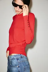 Sweater de punto liso color rojo, con cuello redondo, manga larga y detalles de botones dorados en los puños.