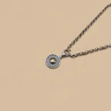 Collar de plata con dije circular con diseño griego y centro dorado.