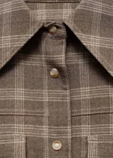 Camisa de estilo abrigo con diseño de cuadros, cuello camisero, cierre frontal con botones y dos bolsillos de parche en el pecho. Presenta manga larga con puños abotonados y un diseño de corte recto.