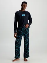 Conjunto de pijama Calvin Klein compuesto por una remera de manga larga negra con logo CK en el pecho y un pantalón largo negro con estampado del logo CK en azul.