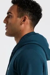 Hoodie de color azul petróleo con capucha, cordones ajustables y bolsillo tipo canguro frontal. Presenta el logo de la marca bordado en el pecho.