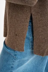 Sweater de punto texturado en color beige, con cuello redondo y mangas largas. Presenta un diseño de tejido acanalado vertical y corte holgado.