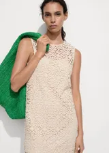 Vestido corto de crochet con diseño de flores, cuello redondo y corte recto. Cuenta con forro interior y diseño sin mangas.