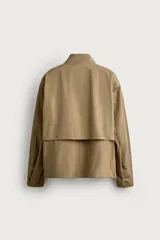 Cazadora regular fit de la colección Aaron Levine x ZARA, confeccionada en tejido con mezcla de algodón con patrón de cuadros pequeños en tonos beige y marrón. Cuenta con cuello subido, manga larga con puño ajustable con botón a presión, bolsillos de vivo en la cadera, bajo ajustable con elástico en los laterales y cierre frontal con cremallera.