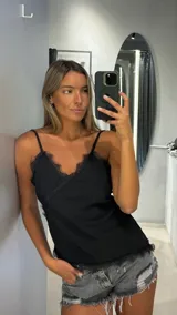 Top negro de tirantes finos con escote en V adornado con encaje negro.