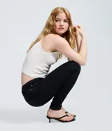 Pantalón skinny de cintura alta confeccionado en jean con elastano, con diseño ajustado, bolsillos delanteros y traseros, y cierre de botón y cremallera.
