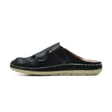 Zueco casual Korium Confort modelo Suria, color negro, confeccionado en cuero con detalles de recortes y costuras visibles en contraste. Cuenta con tira ajustable con velcro en el empeine y suela plana color beige.