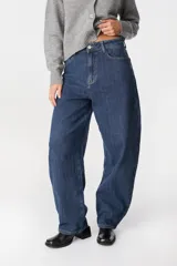 Jean de corte wide leg y tiro alto, confeccionado en denim azul con sutil textura rayada vertical. Presenta diseño de cinco bolsillos, cierre frontal con botón y costuras reforzadas.