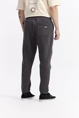 Pantalón de jogging negro de algodón y poliéster, con puños ajustados en los tobillos, cintura elástica con cordón y costuras verticales marcadas en el frente.