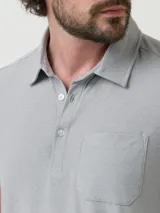 Remera tipo polo de manga corta en color gris melange, con cuello clásico, cierre frontal de tres botones y un bolsillo aplicado en el pecho. Presenta un corte moderno y tejido elástico.
