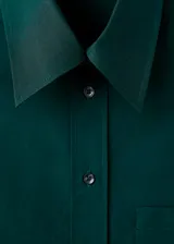 Camisa de popelín de algodón de corte oversize, color verde oscuro, con manga larga, cuello camisero y cierre frontal de botones.