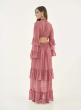 Vestido largo de gasa color rosa viejo, con cuello alto fruncido, cintura elástica tipo nido de abeja y mangas largas con volados. La falda presenta un diseño de capas con volados en el ruedo.
