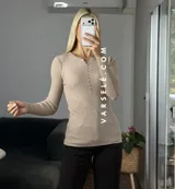 Remera de punto acanalado con escote redondo y cierre frontal parcial con botones. Presenta mangas largas y un ajuste entallado al cuerpo.