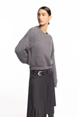 Buzo de punto inglés grueso en color gris melange, de corte amplio con hombros caídos y mangas largas, con sutil bordado de la marca en el pecho.