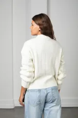 Sweater de punto color blanco, con cuello redondo y diseño de textura trenzada en relieve. Presenta mangas largas con puños ajustados y corte clásico.
